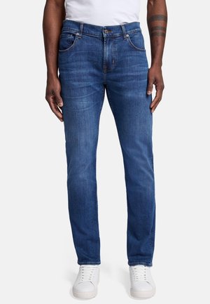 Dark blue denim jeans with a straight-fit design, five pockets, and a slightly faded texture. Paired with white sneakers.