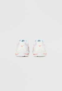 Λευκά αθλητικά παπούτσια με ροζ λεπτομέρειες, επάνω μέρος από διχτυωτό υλικό, επενδεδυμένος γιακάς και υφή στην σόλα. Στρογγυλεμένο σχέδιο με ελαφριά εμφάνιση.