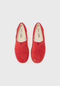 Pantofi slip-on din suede roșu cu detalii cusute în cruce și vârf rotunjit. Interior căptușit cu un material de culoare deschisă, având o branț moale.