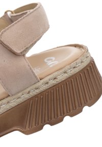 Beige suede platform sandal with adjustable strap, textured brown sole, and cushioned footbed for comfort and support.
