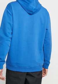 Blå huvtröja i mjuk bomullsblandning med långa ärmar, ribbade muddar och nederkant, samt en avslappnad passform. Sömlös huva för ökad komfort.