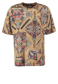 Kortärmad t-shirt med en tan-baserad färg med intrikata geometriska och tribal mönster i svart, röd och teal. Mjuk, lättvikts tyg.