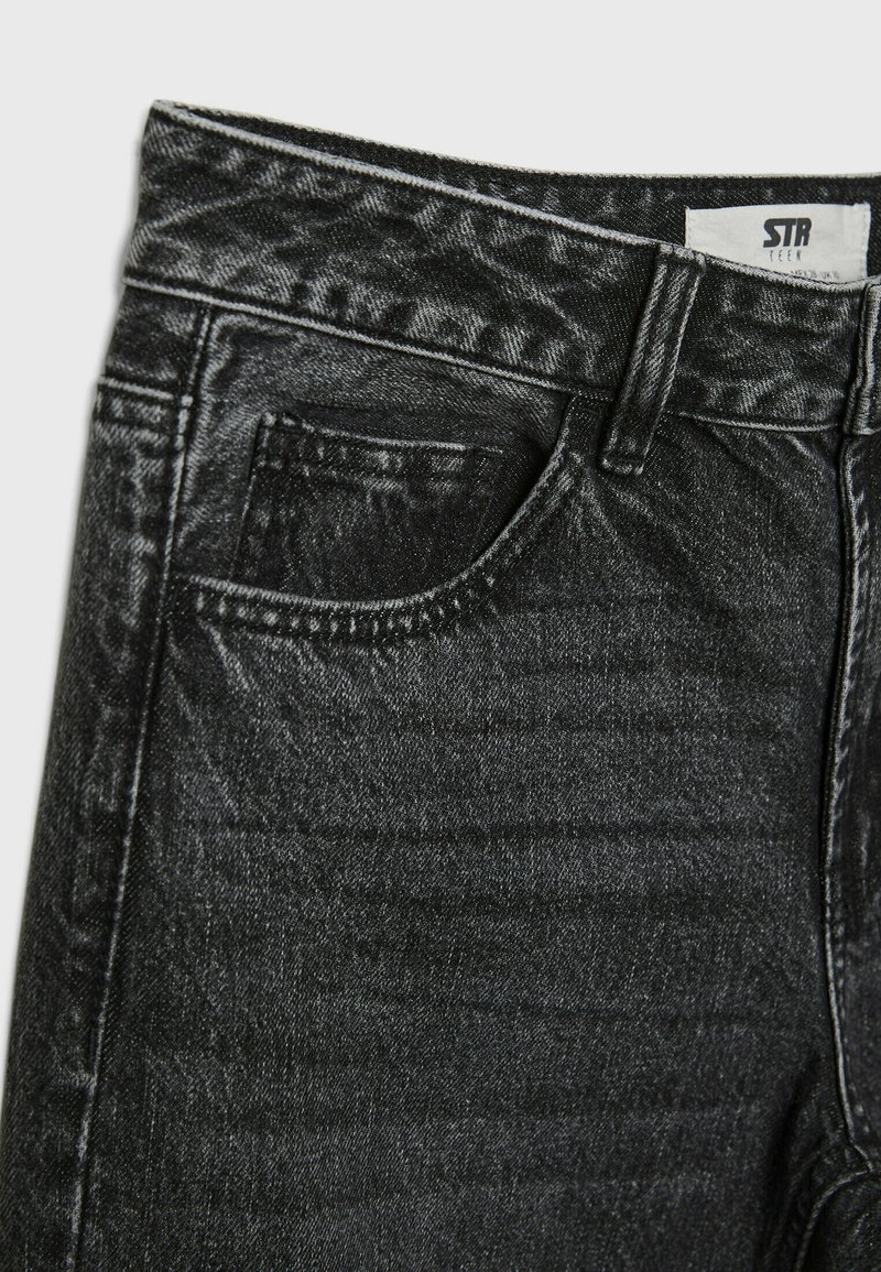 Jeans in denim nero con finitura testurizzata. Presentano una vita standard, un design a cinque tasche e cuciture a contrasto lungo le cuciture.