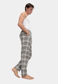 Grijze geruite loungebroek met een elastische tailleband, zijzakken en een relaxte pasvorm, gecombineerd met een aansluitend witte top.