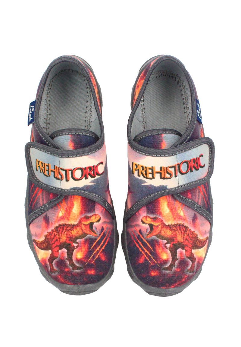 Chaussures en textile arborant un motif de dinosaure vibrant en rouge et orange sur fond sombre. Sangle réglable avec l'étiquette "PRÉHISTORIQUE".