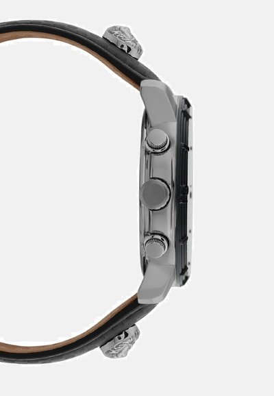 Montre chronographe avec un bracelet en caoutchouc noir, un boîtier en acier inoxydable, trois poussoirs et un cadran rond avec des détails intriqués.
