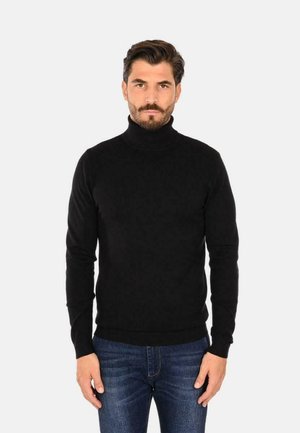 Maglione aderente nero a collo alto realizzato in morbido materiale, caratterizzato da una silhouette slim e orli e polsini a coste, abbinato a jeans blu.