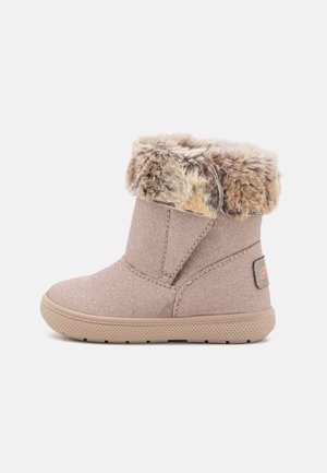 Faux fur-lined ankle boot in light beige textile with a rubber sole. Features a side zipper for easy wear and a small logo patch.