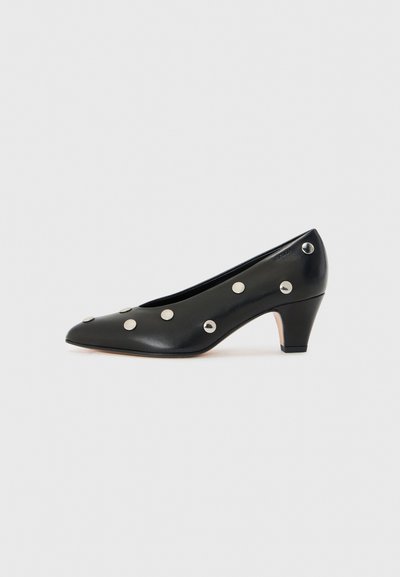 Zwarte leren pump met een spitse neus, een middelhoge hak en gelijkmatig geplaatste zilveren studs op het oppervlak voor decoratieve details.
