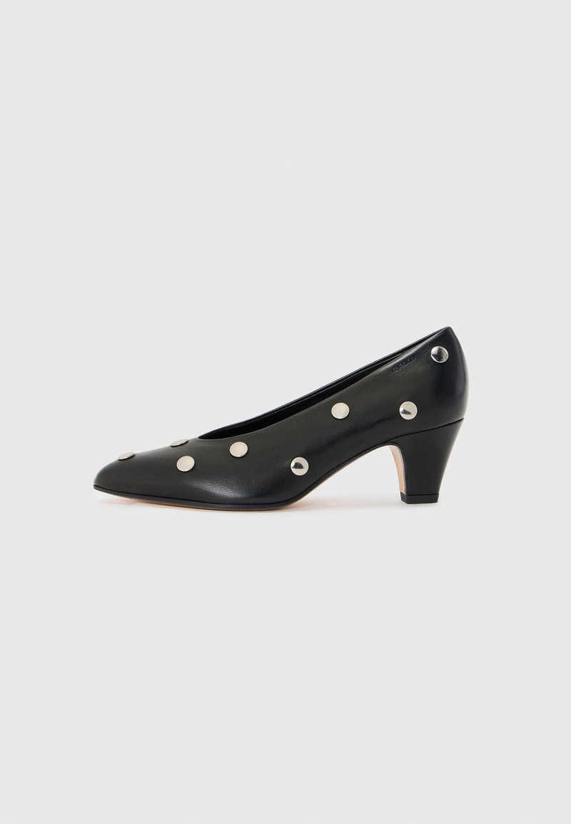 Black leather pump with a pointed toe, mid-heel, and silver studs evenly placed on the surface for decorative detail.