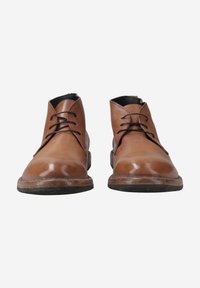 Bottines en cuir marron avec une finition lisse, à bout rond et à lacets. Présentent un intérieur noir contrastant et des semelles en caoutchouc durables.