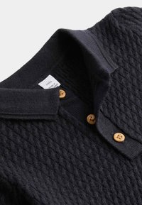 Marine strikket polo skjorte med et tekstureret mønster, krave og fire træknapper ved knaplåsen. Plejeetiket vedhæftet.