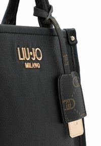 Zwarte leren handtas met een gouden "LIU-JO MILANO" logo, gestructureerde afwerking, bijpassende band met een decoratieve label en gouden sierstukken.