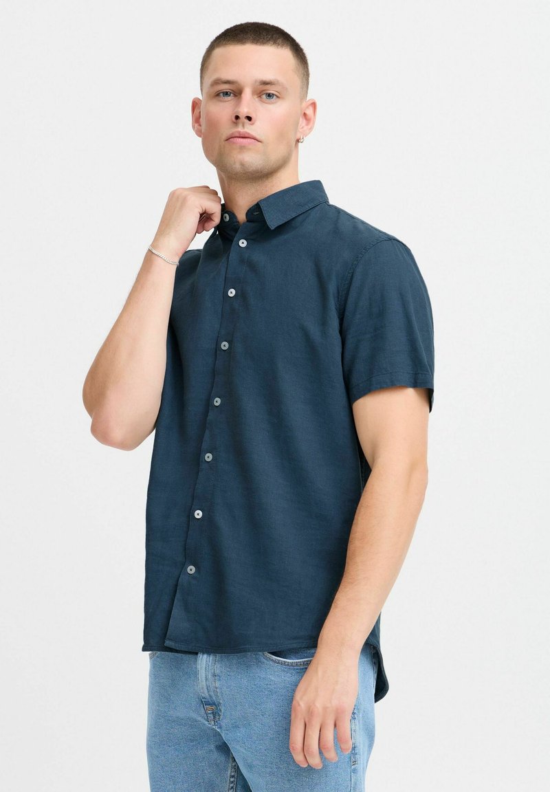Chemise à manches courtes, bleu marine, avec des boutons, fabriquée en tissu léger, dotée d'un col pointu et de boutons contrastants.