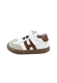 Zapatilla blanca con detalles en marrón, correa de velcro y detalles en ante gris. Punta redonda, suela de goma texturizada y detalles de costura.