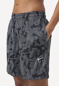 Shorts de sport noirs avec un motif abstrait blanc texturé. Dotés d'une taille élastique et de poches latérales. Logo Nike visible à l'ourlet.