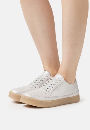 Metalliske sølv sneakers med rund tå, snørebåndsdesign, textureret overdel og lys tan gummisål. Glat finish med subtile detaljer.