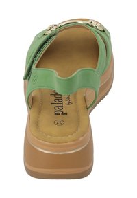 Infradito verdi con una parte superiore liscia e un design a strappo ondulato. Presenta una soletta imbottita e una suola marrone spessa con una leggera elevazione.