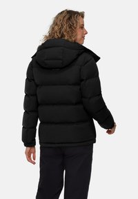 Svart pufferjacka med huva, med en quiltad design, elastiska ärmslut och en matt yta. Varumärkeslogotypen är placerad på den övre delen av ryggen.