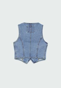 Denimväst med ärmlös design, synlig sömnad och en fyrkantig lapp på den övre ryggdelen, visad mot en ljusgrå bakgrund.