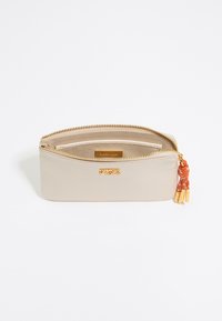 Beige leather pouch with a gold zipper, featuring a textured finish and an orange tassel accent. Logo displayed on the front.