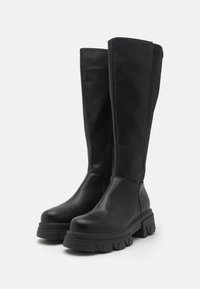 Stivali neri al ginocchio realizzati in pelle liscia, dotati di una suola piatta chunky con un motivo a zigzag e chiusura con zip laterale.
