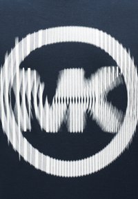 Logo circulaire blanc avec les lettres floues et rayées verticalement "wrx" sur un fond en tissu bleu foncé.