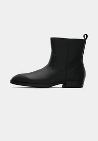 Čierna kožená ankle boot s nízkym podpätkom, okrúhlou špičkou, ťahacím pútkom vzadu a hladkým povrchom na jednofarebnom svetlom pozadí.