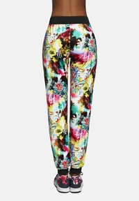 Spodnie dresowe w kwiatowy wzór w żywych kolorach, z czarnym elastycznym pasem i ściągaczami na kostkach, wykonane z lekkiego, elastycznego materiału.