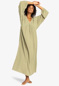 Lange, loszittende jurk van zacht olijfgroen stof met een v-hals, brede mouwen en een geplooid middel, met een getextureerde, gekreukte uitstraling.