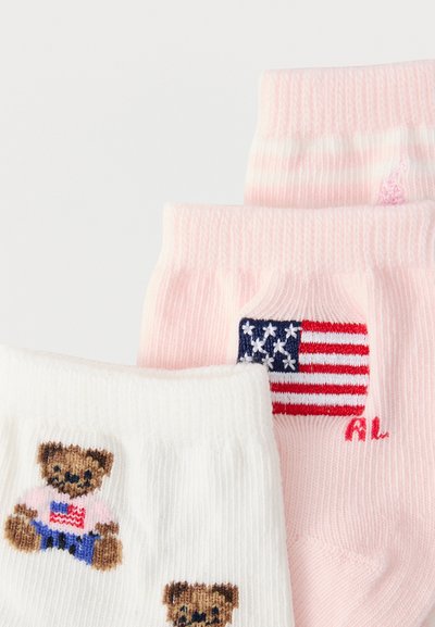 Ζευγάρι ριγωτές κάλτσες, μια ροζ με κεντημένη την αμερικανική σημαία, μια λευκή με αρκουδάκια που φορούν πουκάμισα με την αμερικανική σημαία.