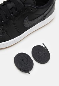 Svart lädersneaker med en texturerad svart Swoosh, vit mellansula och gummisul. Två extra svarta skosnören ingår.