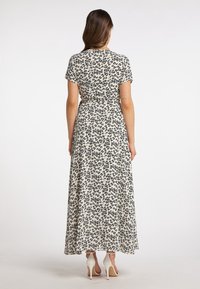 Maxikleid aus leichtem Material, cremefarbener Grund mit einem schwarzen Leopardenmuster, kurzen Ärmeln, tailliertem Schnitt und fließendem Rock.