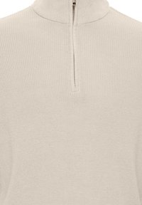 Pull en maille beige clair avec un col montant et une fermeture éclair courte à l'avant. Il présente un motif texturé en côtes sur l'ensemble.