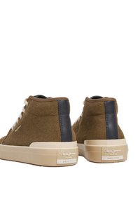 Rudi zomšos aukšti kedai su kreminiais guminiais padu. Akcentai tamsiai mėlynos spalvos ant kulno ir raištelių. Prekės ženklas matomas ant šono ir pado.