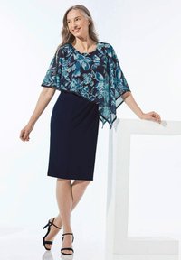 Blumenmuster-Overlay in Blautönen mit durchscheinendem, fließendem Stoff über einem figurbetonten dunkelblauen Kleid. Verfügt über kurze Ärmel und Riemchen-Heels.