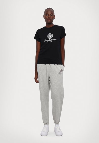 Čierne tričko s krátkym rukávom s bielym logom "Ralph Lauren", skombinované so šedými teplákmi so podobným logom. Biele tenisky.