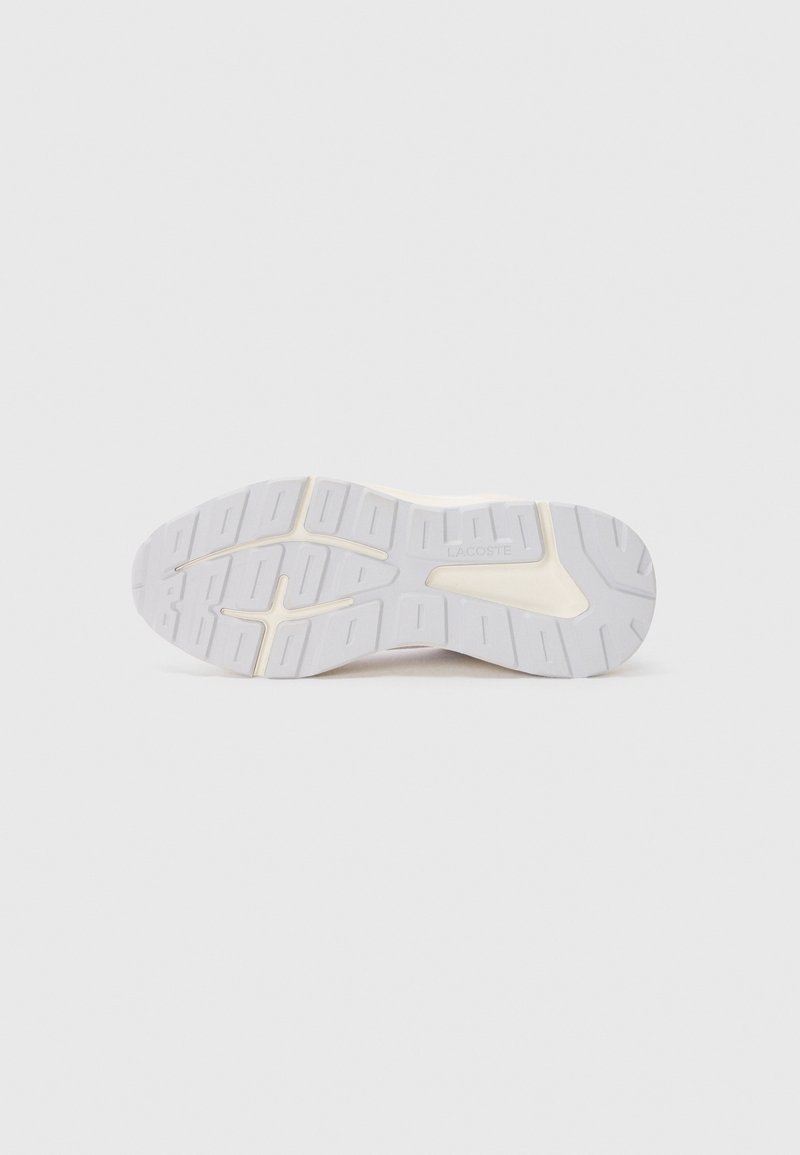 Suola di sneaker bianca con una superficie in gomma testurizzata e scanalature profonde per la trazione, e un accento beige a contrasto lungo i bordi.