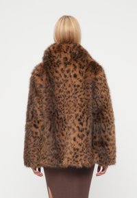 Brauner Mantel aus Kunstpelz mit schwarzen Leopardenflecken, ausgestattet mit einem hohen Kragen und lockerer Passform. Weiche Textur und Ärmel in mittlerer Länge.