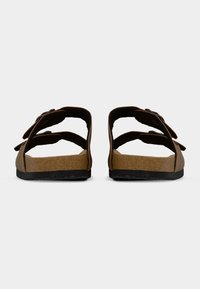 Sandali marroni aperti con due cinturini regolabili, plantare in sughero e suola in gomma nera strutturata. Design e struttura minimalisti.