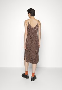 Vestido slip com padrão de zebra castanho, com alças finas, design costas em v e fendas laterais. Combine com meias laranja e sapatos de plataforma pretos para um contraste.