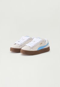 Puma-sko med overdel i lysegrå semsket skinn, hvite snørebånd og blå detaljer. Har en teksturert brun gummisåle. Klassisk lavt design.