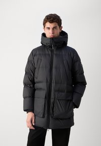 Schwarze Steppjacke mit hochgeschlossenem Kragen, Reißverschluss vorne und zwei großen Fronttaschen. Hergestellt aus langlebigem Material mit gestepptem Textur.