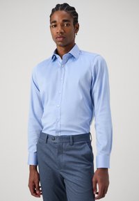 Lichtblauwe overhemd met lange mouwen van gladde stof, voorzien van een klassieke kraag en knopen. Gemaakt in combinatie met slatekleurige, gestructureerde dresspants.
