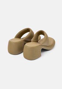 Beige platform-sandaalit, joissa on pyöreä varvasosa, leveät yläremmit ja muotoiltu pohja. Teksturoitu viimeistely kantapäässä lisää yksityiskohtia.