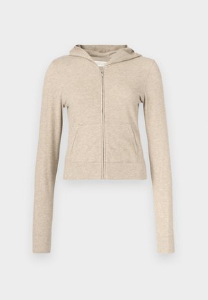 Beige zip-up hoodie with a front pocket, long sleeves, and a soft texture. Features a hood and ribbed cuffs and hem.