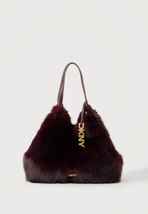 Sac à main en fausse fourrure bordeaux foncé avec poignées en cuir marron et breloque et étiquette dorée avec le logo DKNY à l'avant.