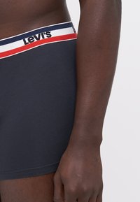 Boxers Levi's de color gris oscuro con una cintura multicolor que presenta rayas azules, rojas y blancas, además de detalles del logo. Tela suave al tacto.
