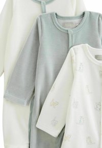 Trois bodies à manches longues en coton doux : un crème, un gris clair et un crème avec des imprimés d'animaux pastel. Boutons-pression à l'avant.