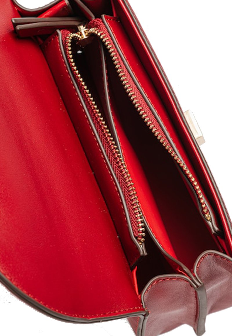 Interior de un bolso de cuero rojo que cuenta con dos compartimentos con cremallera, textura suave, detalles en cremallera en tono dorado y diseño de bordes curvados.